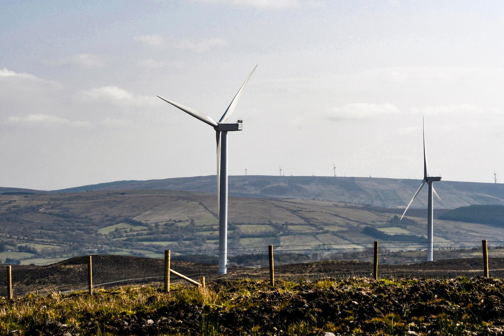 Wind turbines standing in open countryside with rolling hills, showcasing onshore wind energy infrastructure