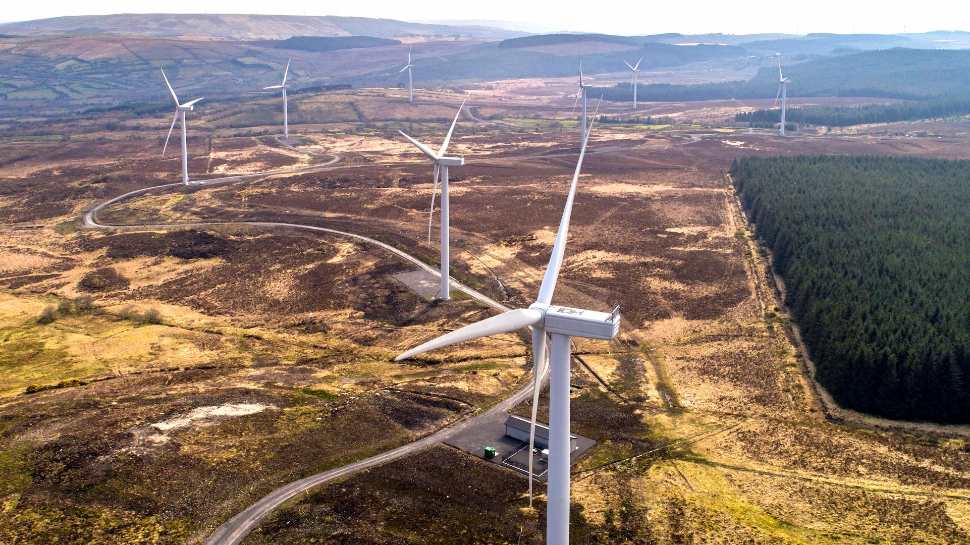 Aerial view of a wind farm with turbines connected by access roads in a remote rural landscape