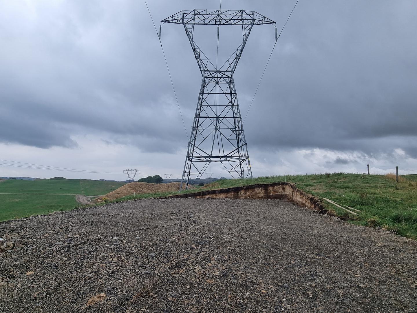 Steel overhead transmission pylon installed on open countryside under cloudy skies