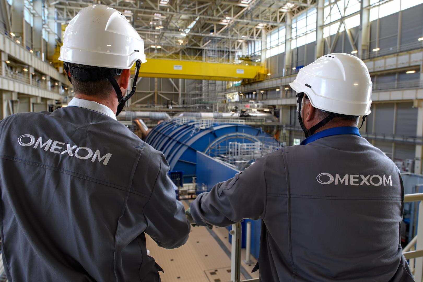 Omexom engineers inspecting heavy electrical and mechanical equipment inside an industrial energy facility
