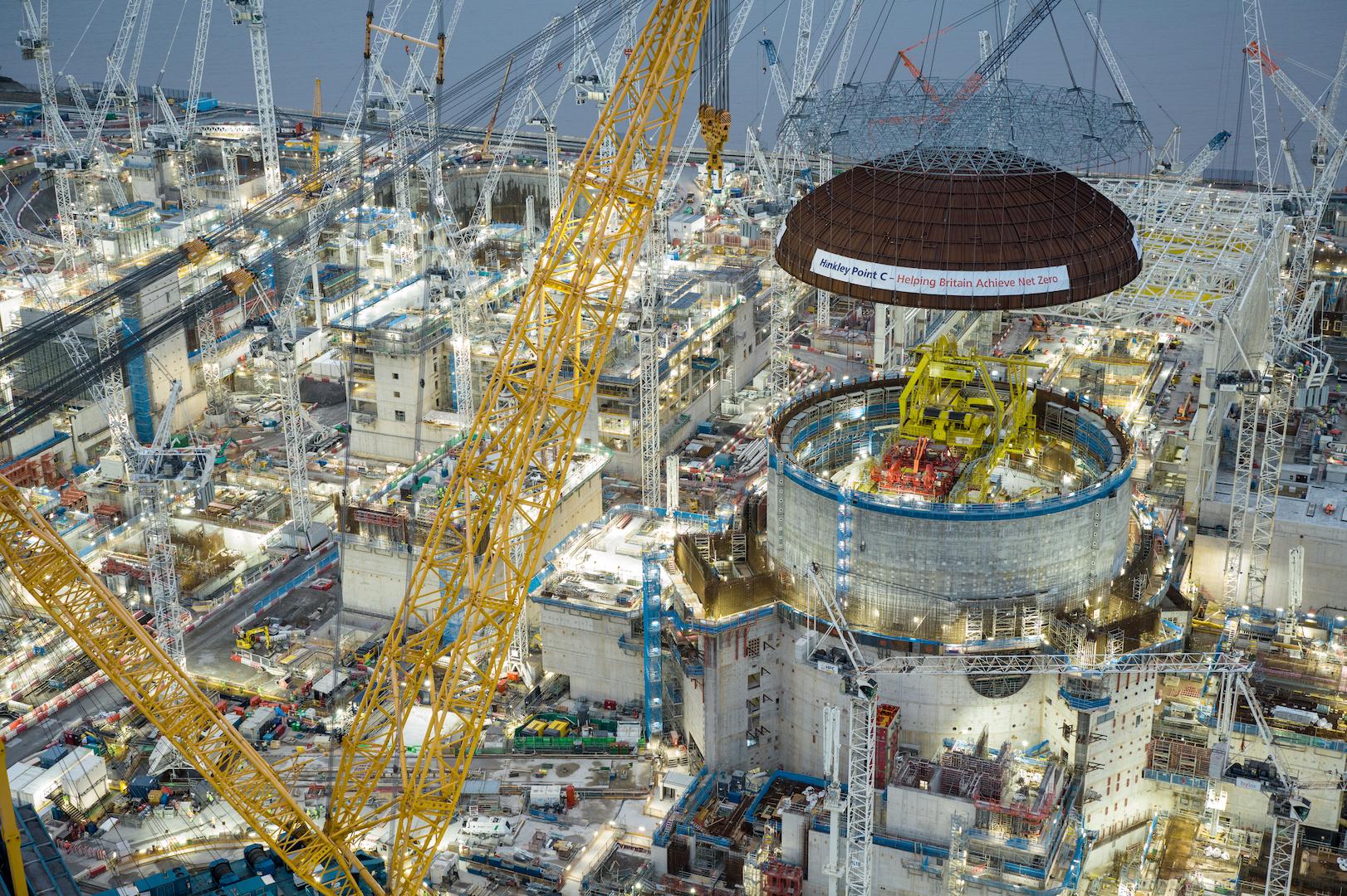 Heavy lifting operation installing a reactor dome using cranes at a nuclear power plant construction site