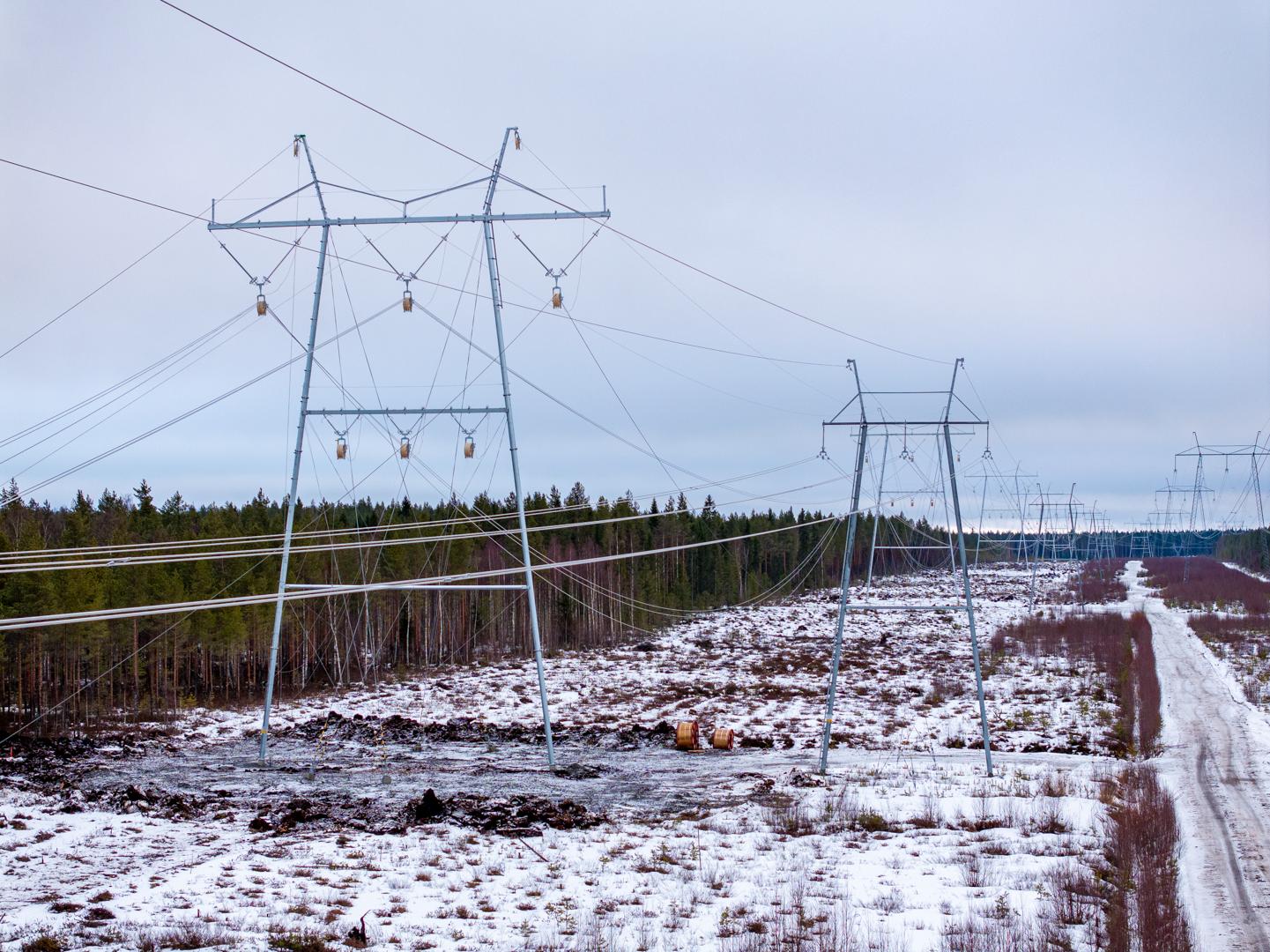 Overhead high-voltage transmission line crossing a snowy forest landscape, illustrating grid expansion in northern conditions