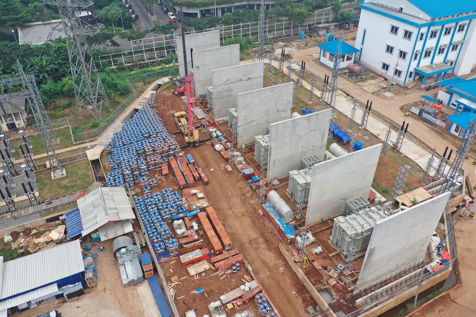 Aerial view of an electrical substation construction site with transformers, concrete fire walls, and grid equipment installation in Indonesia