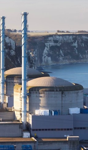 Nuclear power plant with reactor buildings and chimneys near coastal cliffs, illustrating modern energy infrastructure