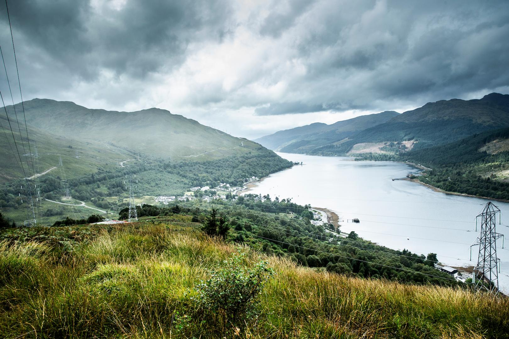 Overhead electricity transmission lines running along a loch and mountainous landscape