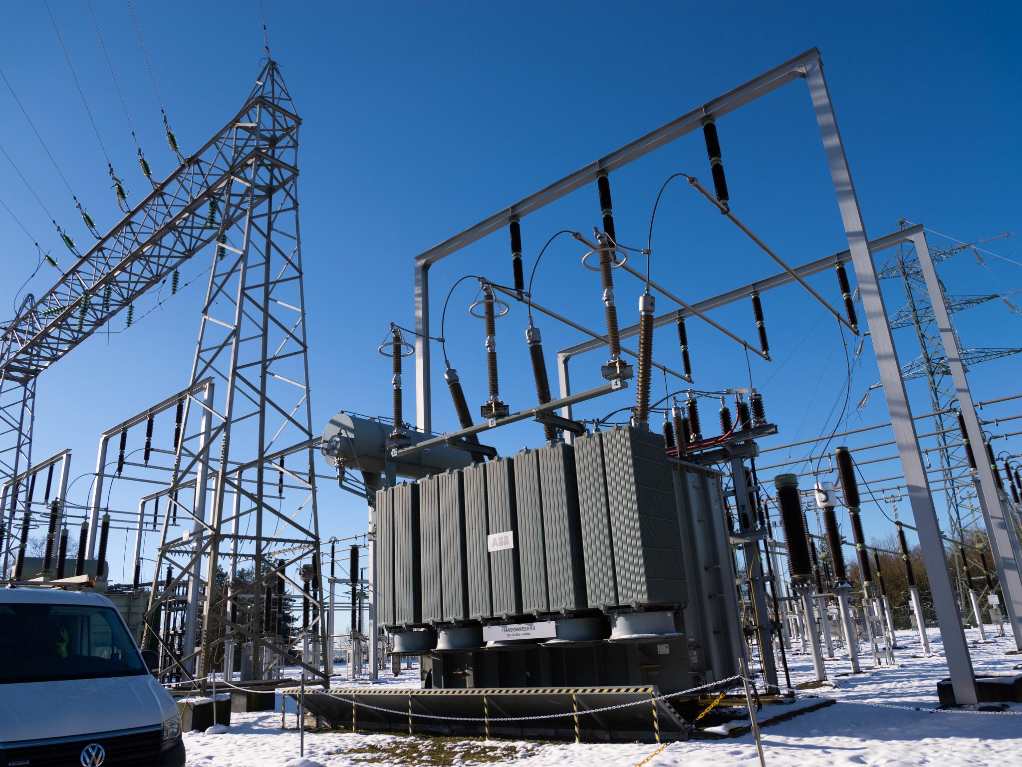 Snow-covered electrical substation with transformer and switching equipment in winter conditions