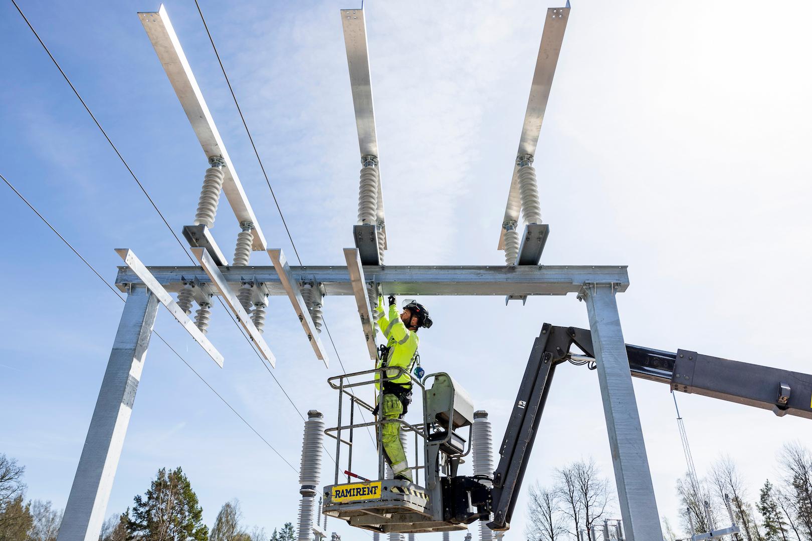 Electrical technician working at height on substation busbars using a lifting platform