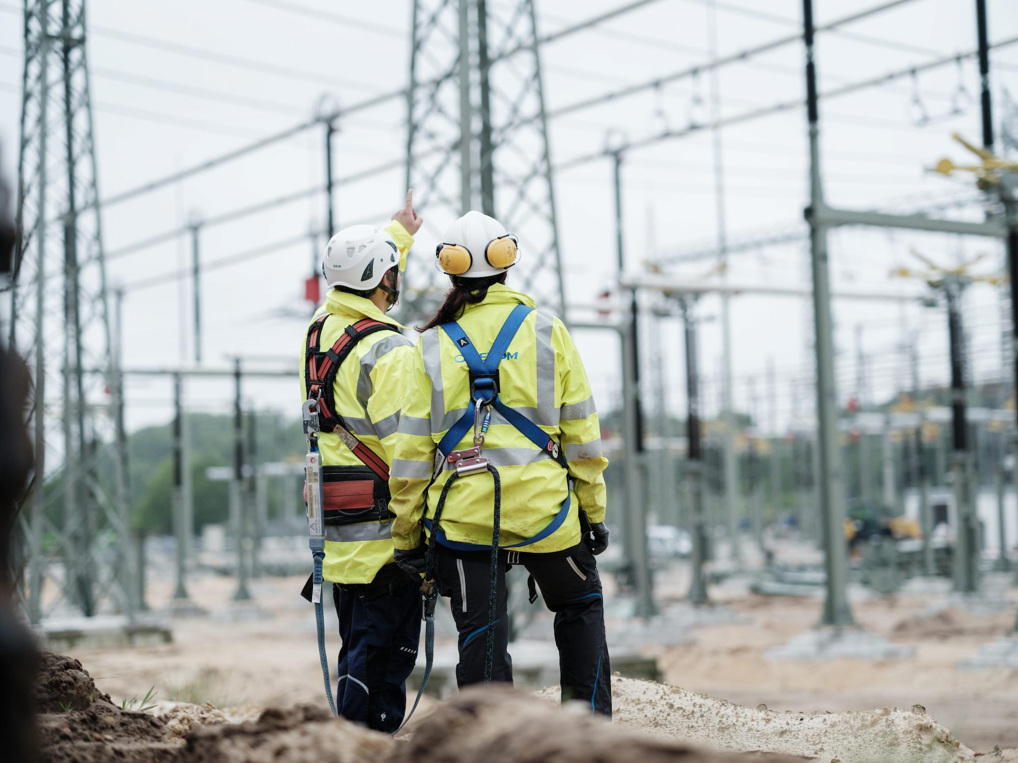Electrical substation site with steel structures, insulators, and transmission lines under construction