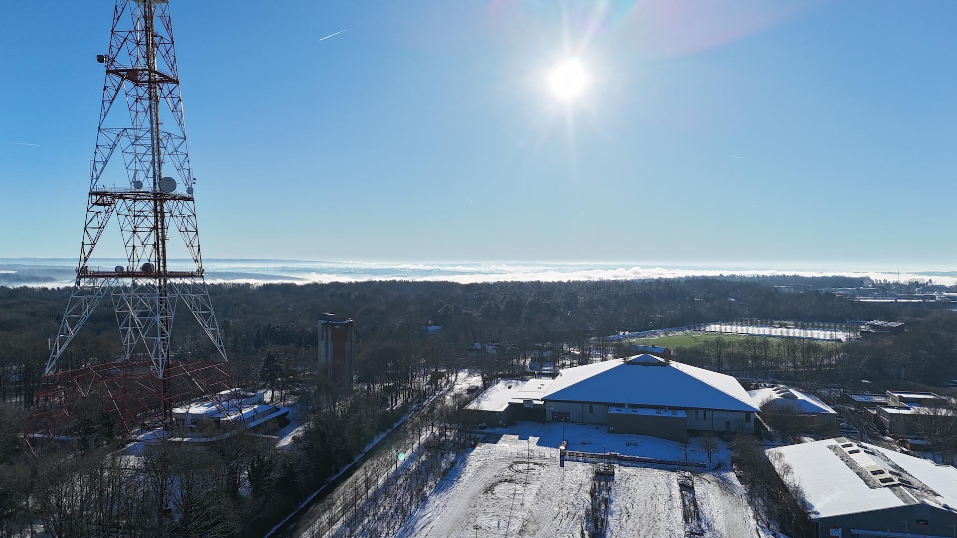 High-voltage transmission infrastructure near an industrial site during winter conditions