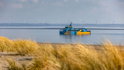 Electric catamaran E-Kat sailing along dune coastline