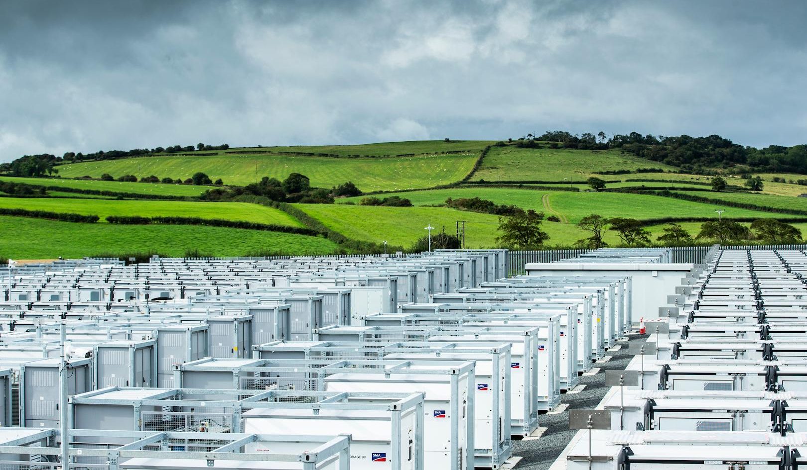 Largescale battery energy storage system installation in a rural landscape with rows of white storage units.