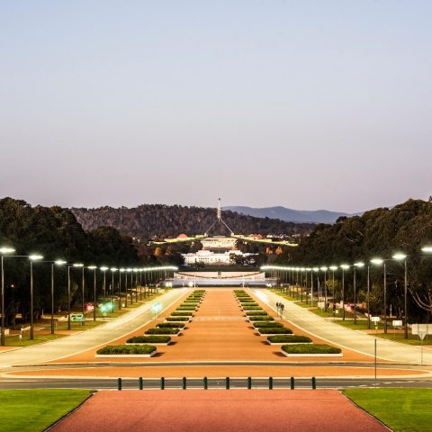 Symmetrical night view of a ceremonial boulevard in Canberra illuminated by aligned street lighting