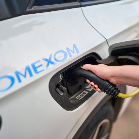 Close-up of an Omexom electric vehicle charging connection, highlighting branded EV infrastructure and reliable charging technology