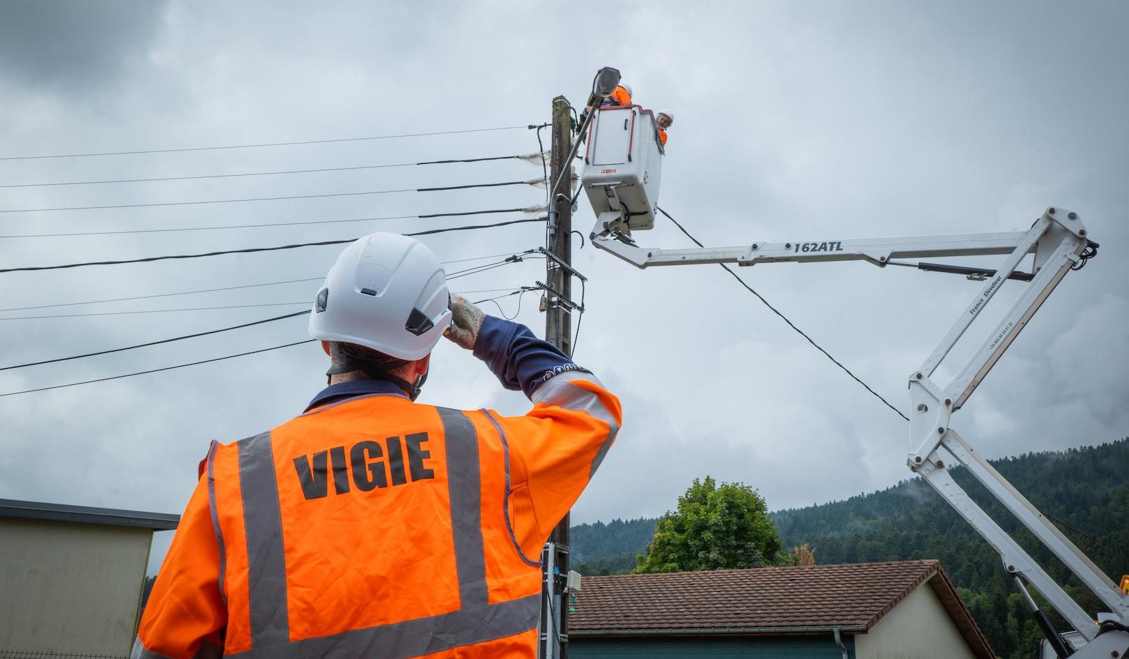 Aerial basket lift operation on overhead power lines supporting a regional electricity distribution service in a residential area