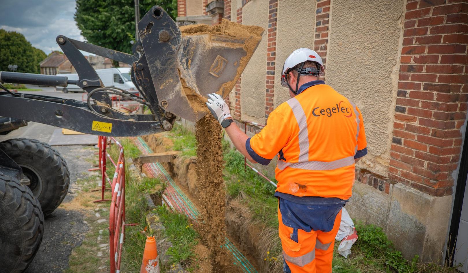 Excavator trenching operation for underground utility network installation, supporting electricity and energy distribution works in an urban environment