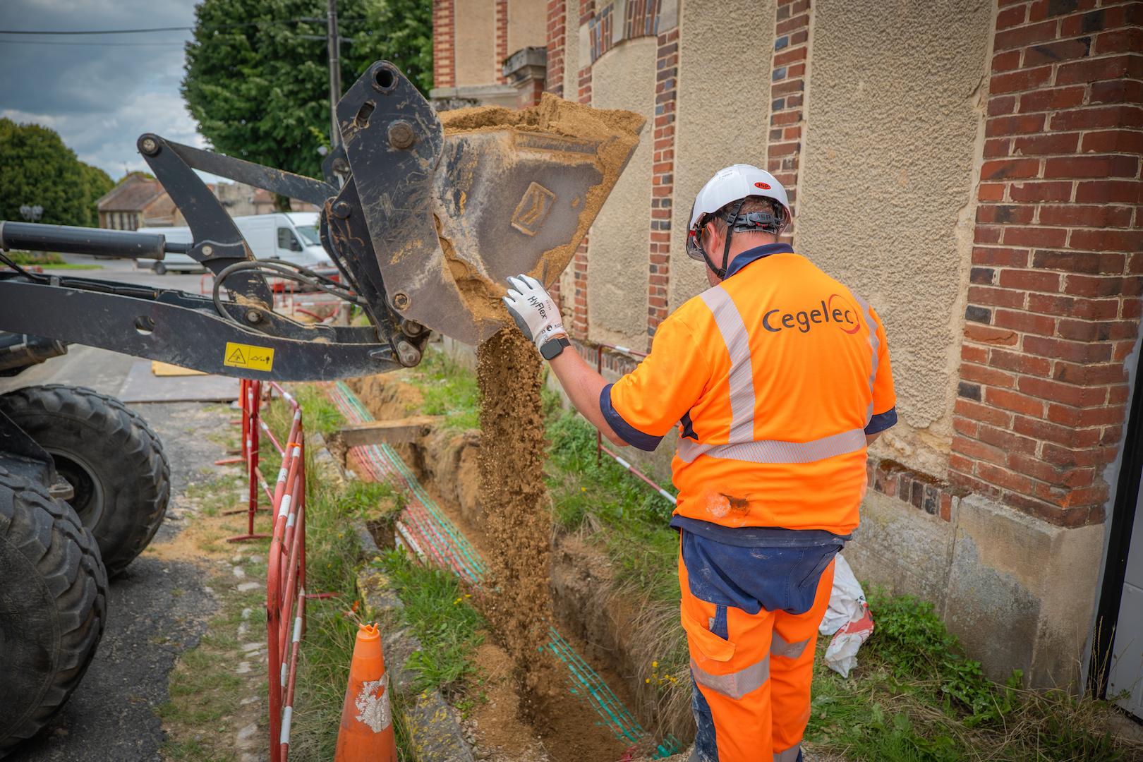 Excavator trenching operation for underground utility network installation, supporting electricity and energy distribution works in an urban environment