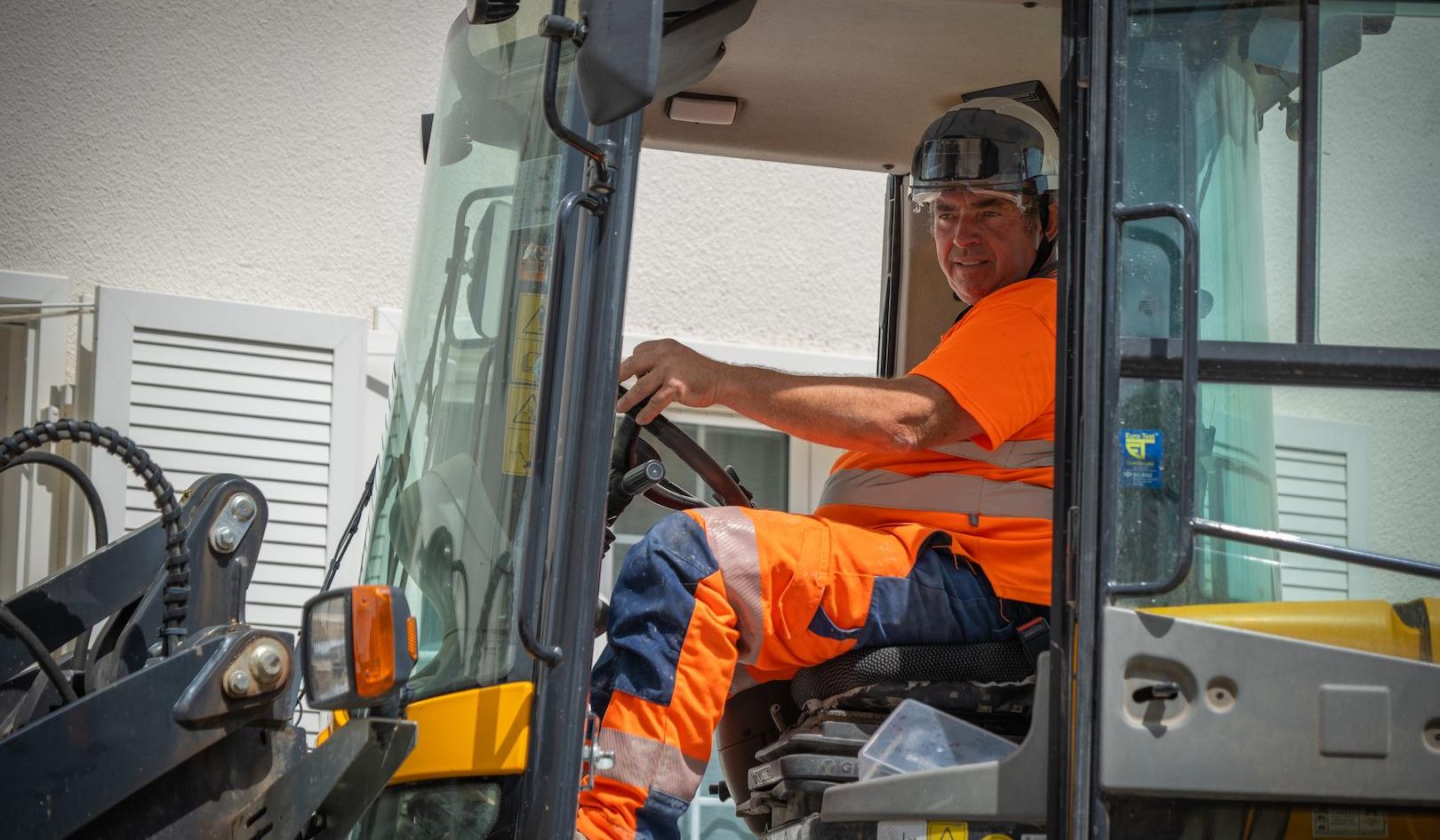 Operator using construction equipment during electricity distribution service works focused on underground network installation