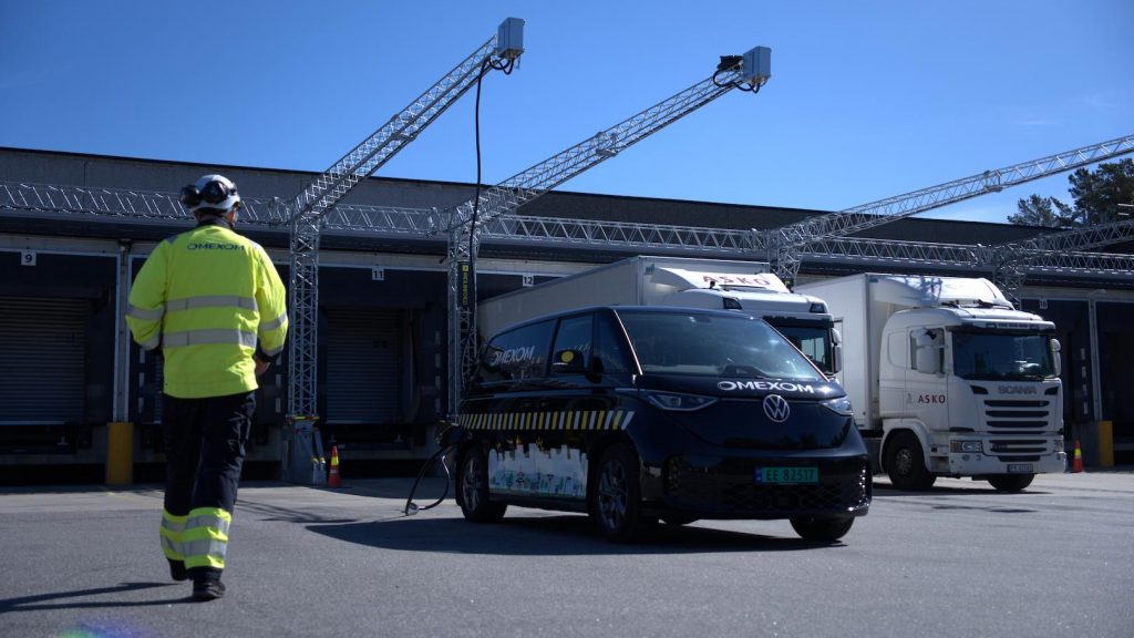 Electric vehicle charging facility at a logistics hub, showing Omexom service vehicles and advanced charging infrastructure for fleet electrification