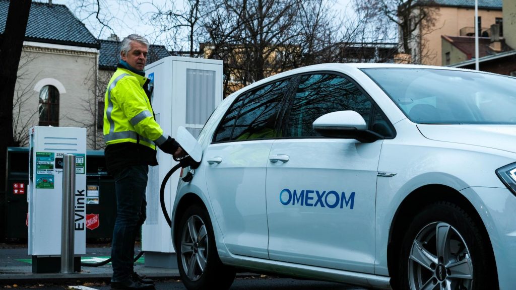Omexom technician operating an electric vehicle charging station, illustrating professional installation and maintenance of EV charging solutions
