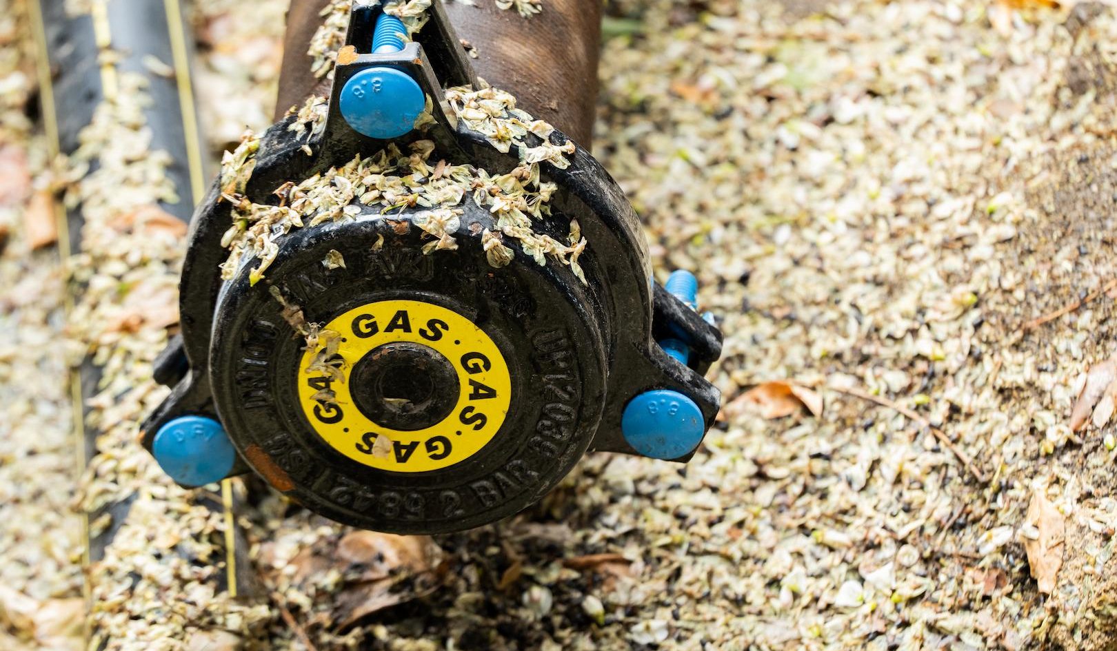 Closeup view of a gas distribution pipe and valve assembly during underground network installation, supporting safe and reliable gas supply infrastructure