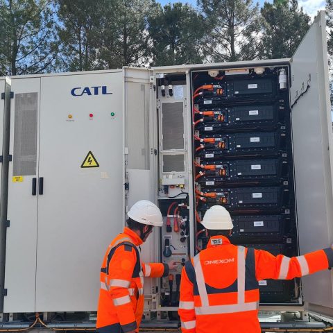 Technicians inspecting CATL battery energy storage cabinets at an outdoor industrial renewable energy site.