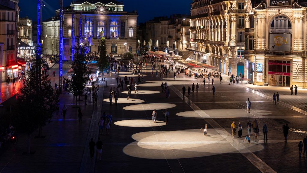 Historic urban plaza at night featuring artistic ground lighting and illuminated public walkways
