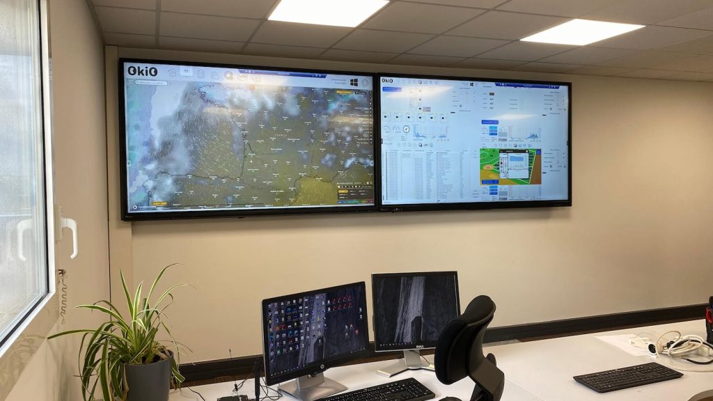 Smart grid control room with real-time network monitoring dashboards and operational software displayed on large wall screens