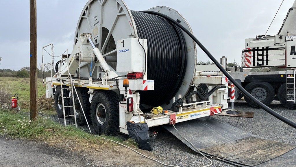 Underground power cable installation using a cable drum trailer and heavy-duty equipment on a construction site
