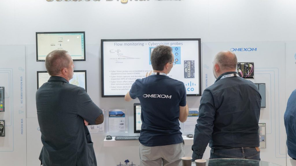 Omexom experts presenting flow monitoring and cybersecurity solutions for smart grids at a secured digital grid stand