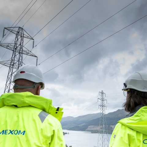 Wide view of workers maintaining overhead high-voltage transmission lines