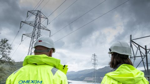 Wide view of workers maintaining overhead high-voltage transmission lines