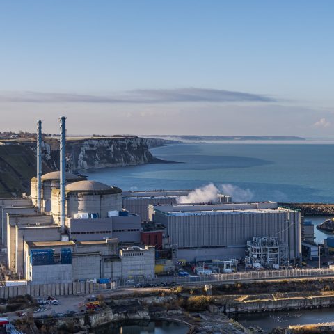 Nuclear power plant with reactor buildings and chimneys near coastal cliffs, illustrating modern energy infrastructure