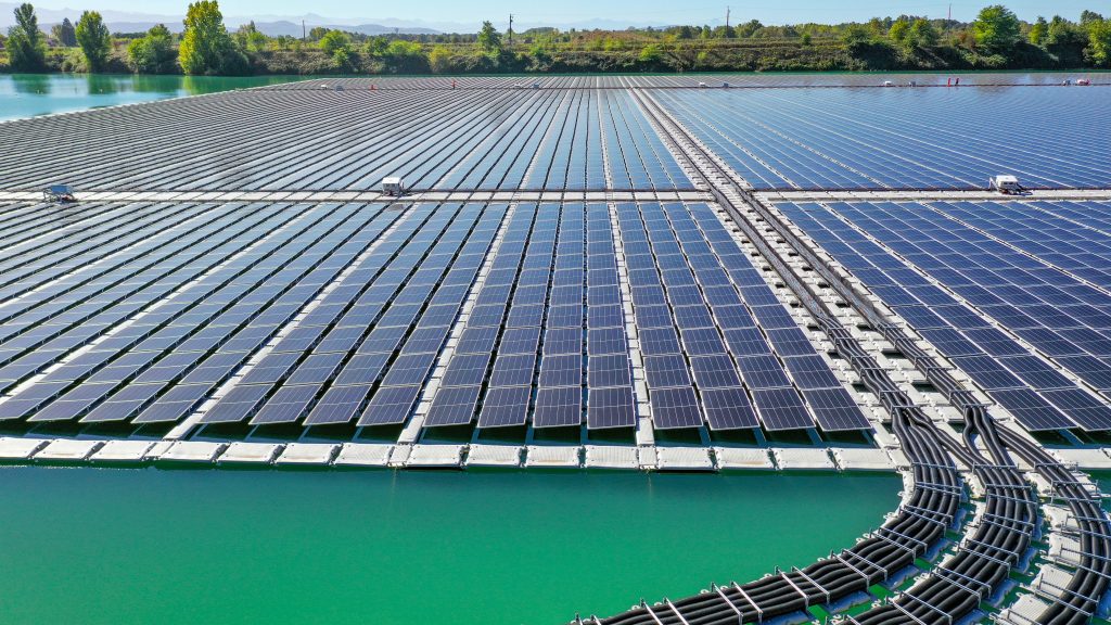 Aerial view of curved floating walkways leading to the solar panel array at the Saint-Élix-le-Château hybrid solar plant on a former quarry lake.