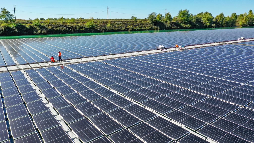 Aerial view of technicians working on a floating walkway between solar panel rows at the Saint-Élix-le-Château plant.